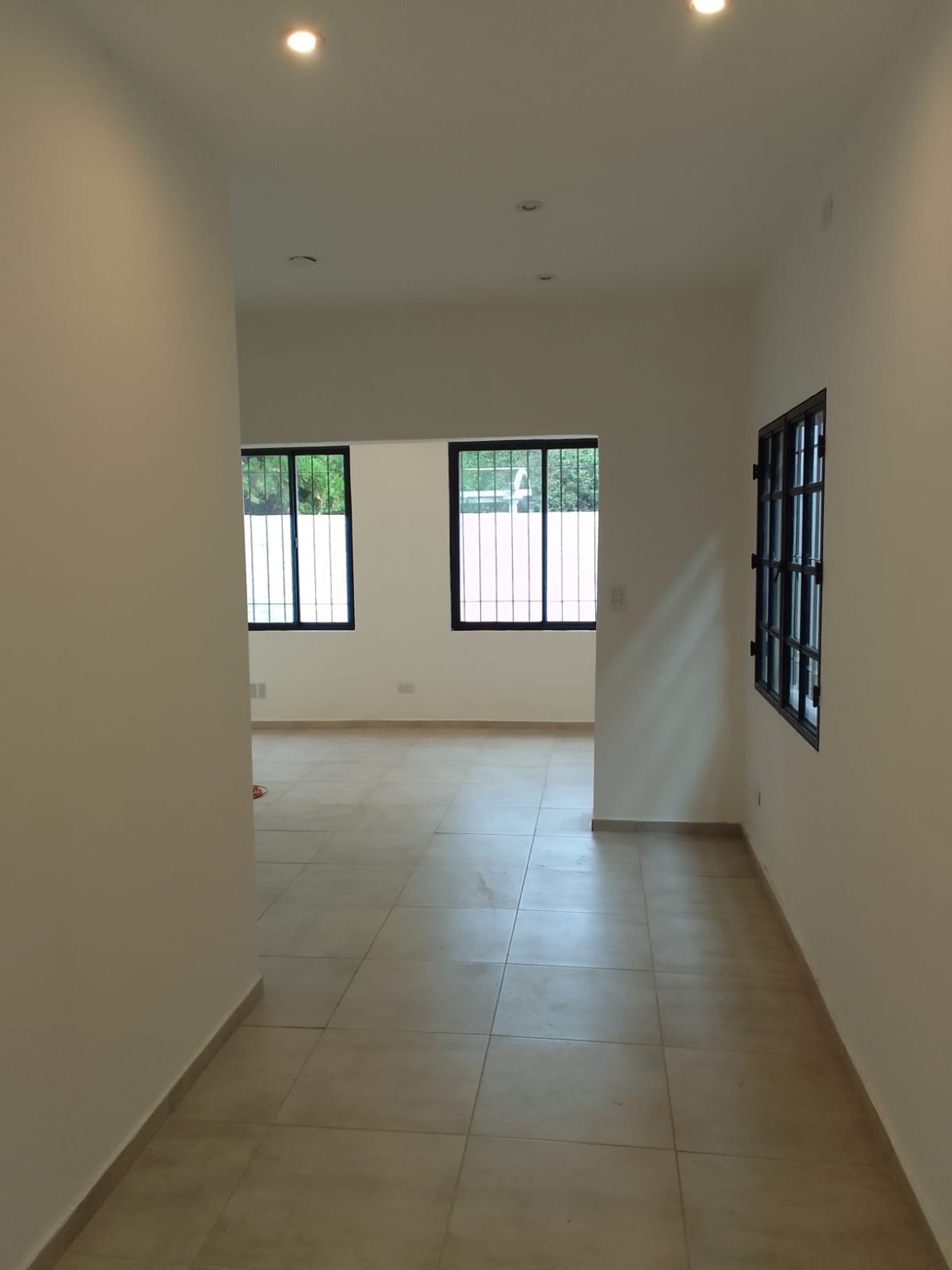 Pasillo moderno con piso de cerámica beige y ventanas — proyecto Casa en Sarandi, por Arquitecto Guido Niccoli, en B1872 Sarandí